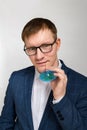 Waist-high portrait of handsome young man in modern glasses holding small cocktail umbrella and looking at camera. Royalty Free Stock Photo