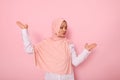 Waist-length portrait of beautiful mysterious Muslim woman wearing a headscarf hijab, showing something on her palms isolated on Royalty Free Stock Photo