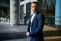 Waist length portrait of a handsome successful businessman developer entrepreneur in business suit with a luggage standing outdoor Royalty Free Stock Photo