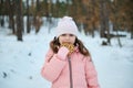 Waist length of a happy child, charming pleasant little girl snacking outdoor while walking on a snowy forest, enjoying cool fresh Royalty Free Stock Photo