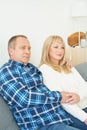 Waist portrait of mature couple in home interior on sofa. Handsome man and middle age woman