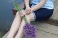 A waist portrait of a woman with a bouquet of Allium. Looks into the camera