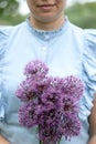 A waist portrait of a woman with a bouquet of wildflowers. Looks into the camera