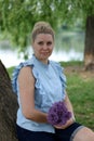 A waist portrait of a woman with a bouquet of wildflowers. Looks into the camera