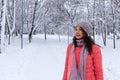 Waist-shot of a happy and stylish beautiful woman in a bright coral jacket, smiling and enjoying a winter day