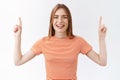 Waist-up cheerful, carefree pretty caucasian woman in striped t-shirt, raising fingers pointing up, promote top Royalty Free Stock Photo