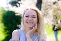 Waist up portrait of young smiling woman with blond hair near blossoming plum tree Royalty Free Stock Photo