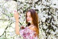 Waist up portrait of young smiling woman with red hair near blossoming plum tree Royalty Free Stock Photo