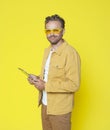 Waist up image of attractive happy smiling middle-aged man using tablet computer in hands isolated on yellow background. Royalty Free Stock Photo