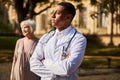 Proud medical professional standing near his elderly patient