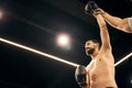 Shirtless boxer standing with his hand in the air