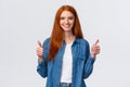 Waist-up portrait alluring confident smiling redhead female blogger review awesome new product, showing thumbs-up in