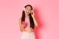 Waist-up portrait of attractive stylish asian girl close eyes and singing along song while listening music in headphones Royalty Free Stock Photo