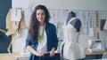 Portrait of beautiful young woman tailor standing in workplace near clothed mannequin and looking at camera. Women& x27;s Royalty Free Stock Photo
