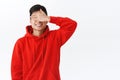 Waist-up portrait of charming young excited asian man, shut eyes with palm and smiling, awaiting for surprise gift Royalty Free Stock Photo