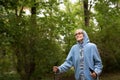 Waist up portrait of elderly woman. Caucasian old lady in blue hoodie and glasses smiling and does nordic walking in the Royalty Free Stock Photo