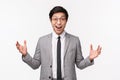 Waist-up portrait of excited, happy young lucky asian man in grey suit, describe something big, stretch hands sideways Royalty Free Stock Photo