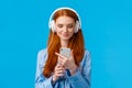 Waist-up portrait good-looking foxy teenage college girl in headphones, listening music, scrolling news feed in morning Royalty Free Stock Photo
