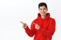 Waist-up portrait of handsome asian man in red hoodie give advice where find good company to get job, employement or