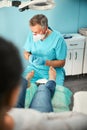 Chiropodist in uniform holding nail instrument in hand