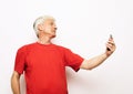 Waist up portrait happy pensioner holding his phone in outstretched hand and laughing. Royalty Free Stock Photo