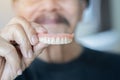 Waist up portrait of the old happy man in black t-shirt showing model of human teeth Royalty Free Stock Photo