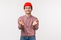 Waist-up portrait pleasant funny young man with beard in red beanie, holding hands as if ready to receive something, get