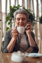 Relaxed aged woman talking on phone in cafe