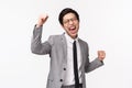 Waist-up portrait of relieved, successful asian young businessman, male entrepreneur in gray suit, fist pump, do