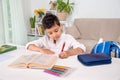Waist up portrait of a  schoolboy siting at the table at home and doing his homework Royalty Free Stock Photo