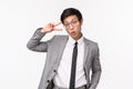 Waist-up portrait of silly and funny asian young man in grey suit, formal outfit, showing peace kawaii sign and folding Royalty Free Stock Photo