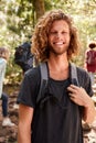 Waist up portrait of smiling millennial white man hiking in a forest, close up, vertical