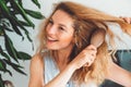 Waist up portrait smiling woman brushing her blonde curly hair with a hair brush Royalty Free Stock Photo