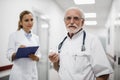 Old doctor and nurse standing in hospital hallway