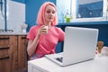 Girl with pink hair drinking her morning matcha tea and working at her laptop Royalty Free Stock Photo