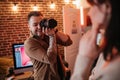 Happy tattooed photographer taking picture of model in the loft studio Royalty Free Stock Photo