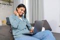 Waist up portrait view of relaxed female freelancer comfortably sitting on the couch in the living room, typing email on