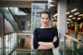 A portrait of young businesswoman standing in corridor outside office, arms crossed. Royalty Free Stock Photo