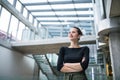 A portrait of young businesswoman standing in corridor outside office, arms crossed. Royalty Free Stock Photo