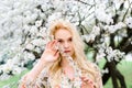 Waist up portrait of young smiling woman with blond hair near blossoming plum tree Royalty Free Stock Photo