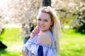 Waist up portrait of young smiling woman with blond hair near blossoming plum tree Royalty Free Stock Photo