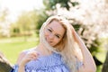 Waist up portrait of young smiling woman with blond hair near blossoming plum tree Royalty Free Stock Photo