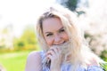 Waist up portrait of young smiling woman with blond hair near blossoming plum tree Royalty Free Stock Photo