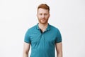 Waist-up shot of attractive masculine macho man with ginger hair in green polo shirt smirking and gazing with confident