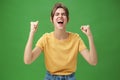 Waist-up shot of charismatic energized and excited female in yellow t-shirt closing eyes yelling from joy and happiness