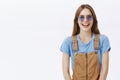 Waist-up shot of charming happy and amused european brunette in brown overalls and stylish sunglasses laughing joyfully
