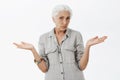 Waist-up shot of clueless unsure cute granny with white hair shrugging with hands spread aside being questioned and Royalty Free Stock Photo