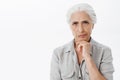 Waist-up shot of concerned serious-looking perplexed elderly woman with grey hair frowning and smirking from Royalty Free Stock Photo