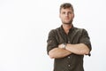 Waist-up shot of confident good-looking male entrepreneur with blond stylish hairstyle and blue eyes cross hands over