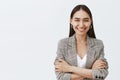 Waist-up shot of confident happy female entrepreneur in stylish jacket over t-shirt, holding hands crossed on chest in